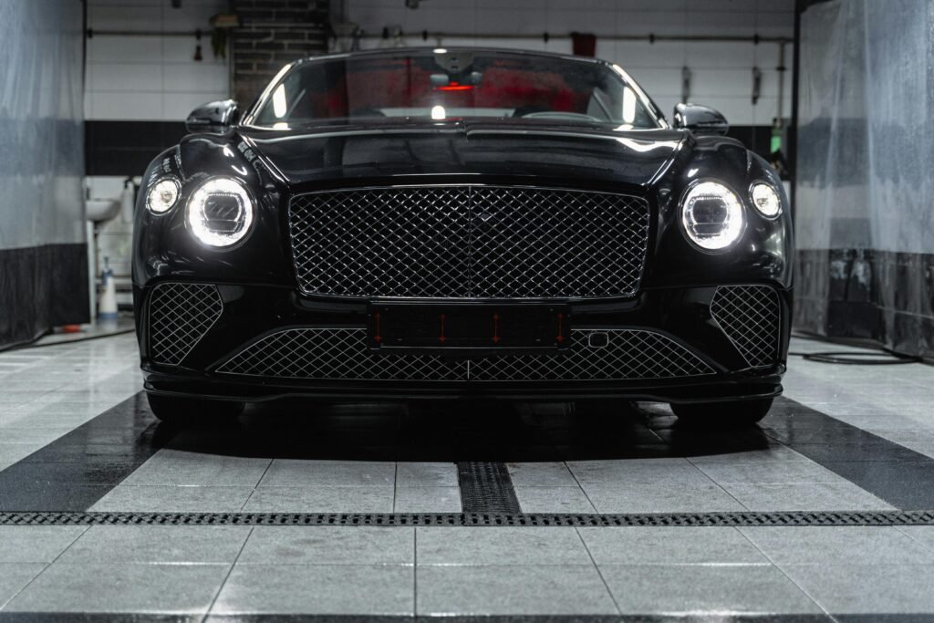 Front view of a sleek black Bentley inside a car wash, showcasing elegance and luxury.